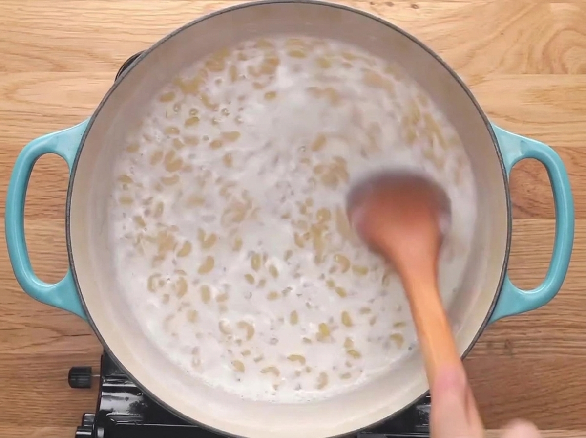 牛乳で煮込まれるマカロニを木べらで混ぜている様子