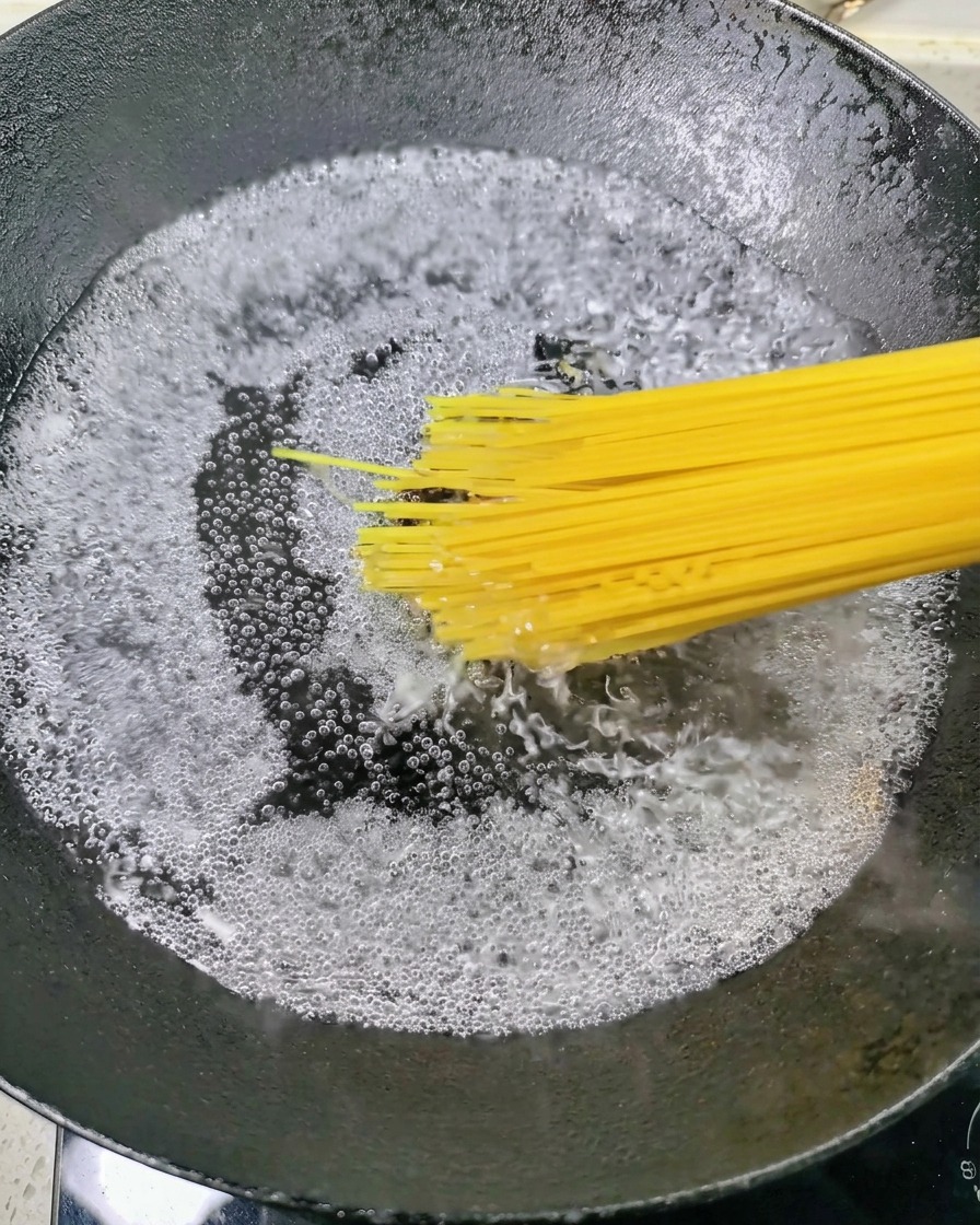 激しく沸騰したお湯の入った鍋に、乾燥スパゲティを入れようとしている様子。