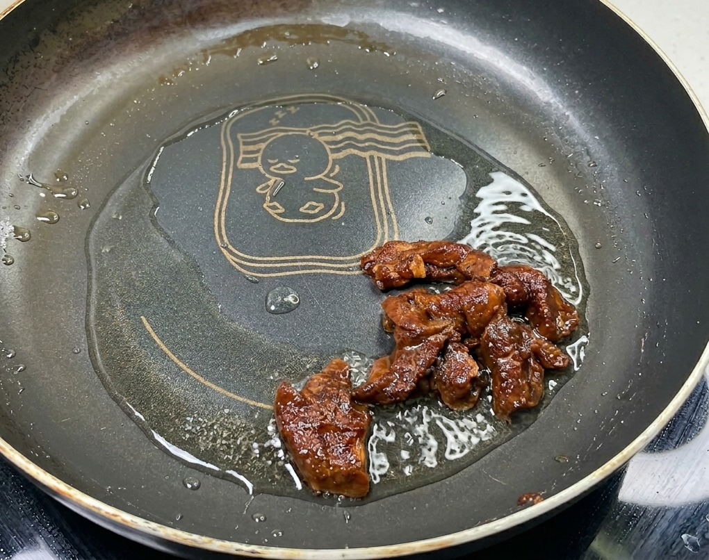フライパンにひいた油で炒められ、豊かな茶色とツヤのある表面に仕上がっていく味付け済みの豚肉。