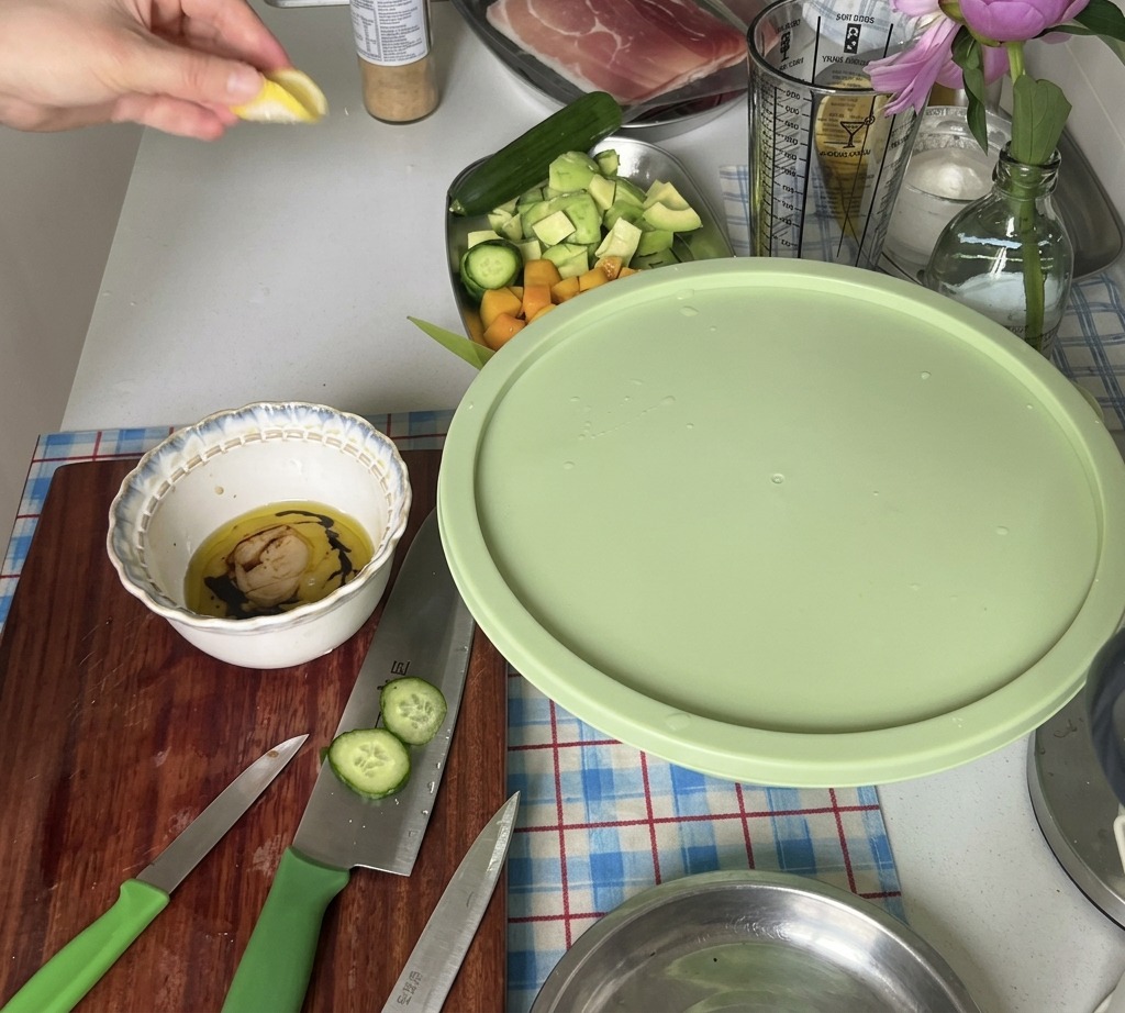 サラダドレッシングの材料が入った小さなボウルに、新鮮なレモンを片手で絞って果汁を入れている様子。