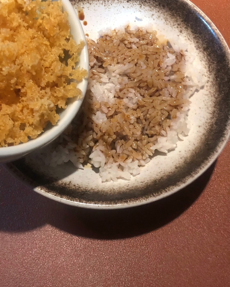 タレのかかったご飯に天かすをふりかけている様子。