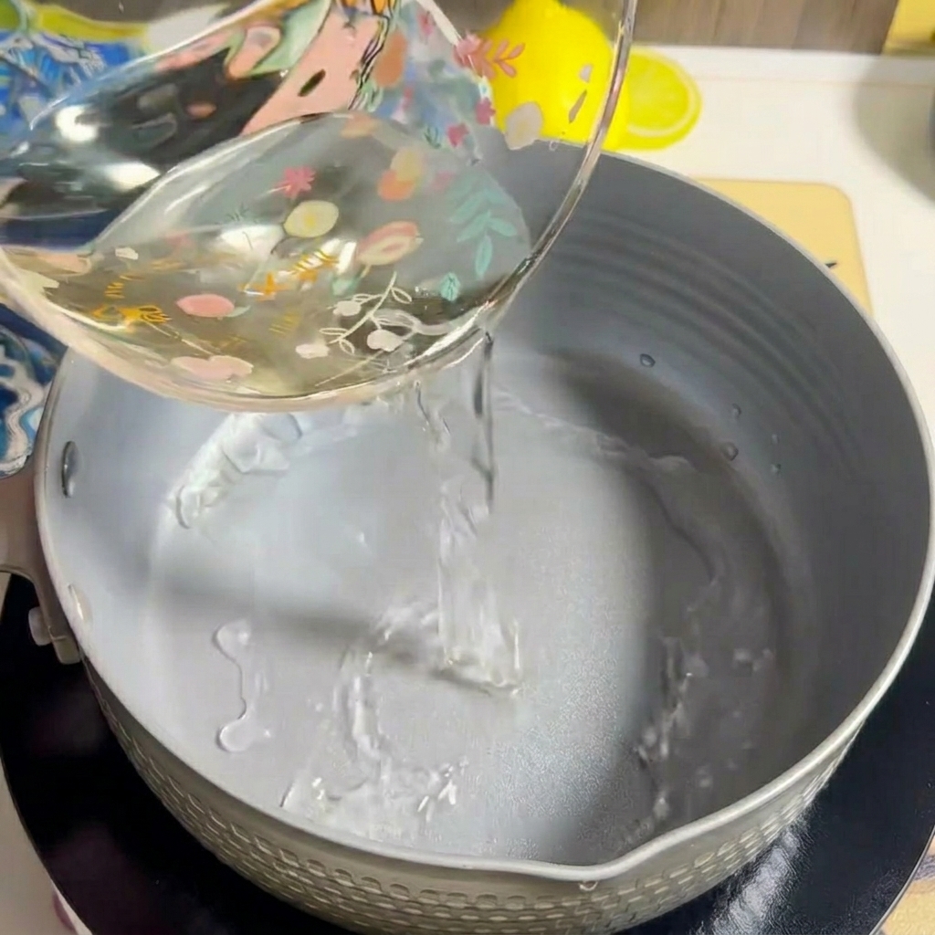 コンロの上の鍋に水が注がれている様子