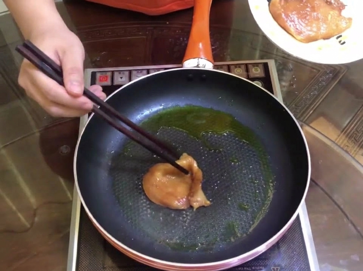 フライパンで肉を焼いている様子。
