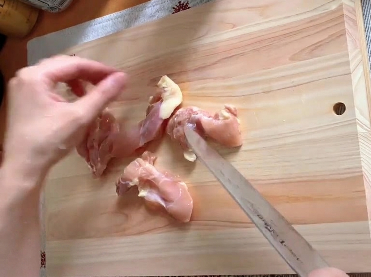 まな板の上で鶏もも肉をカットしている様子。