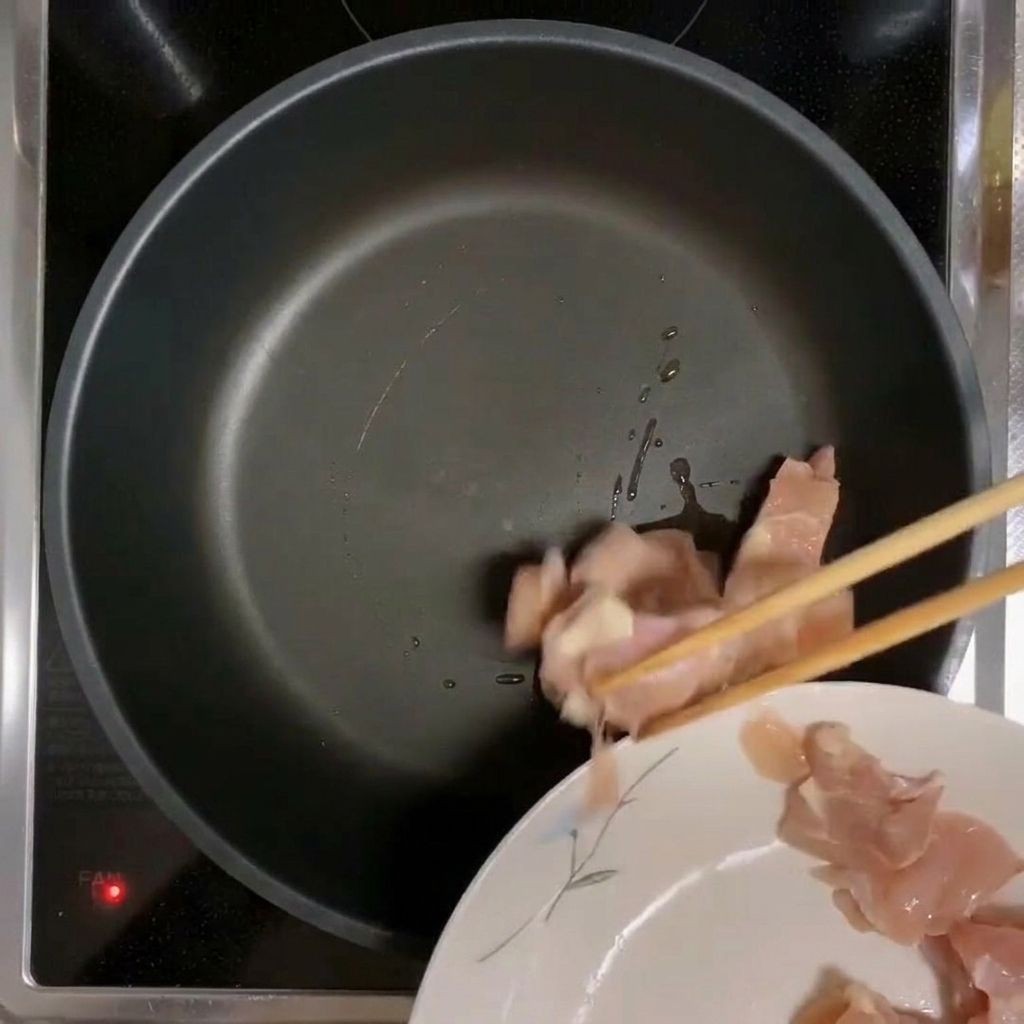 熱したフライパンで鶏肉を焼いている様子。