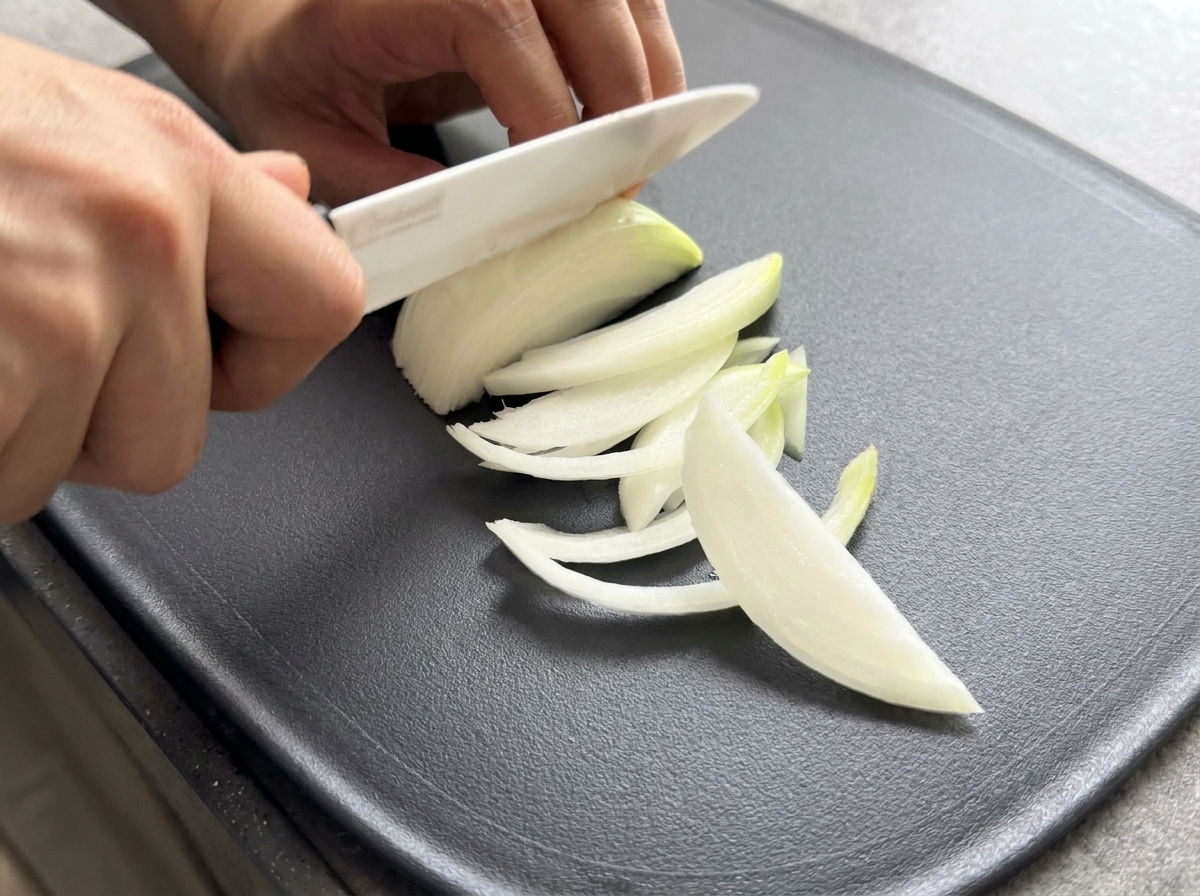 まな板の上で玉ねぎを薄切りにしている様子