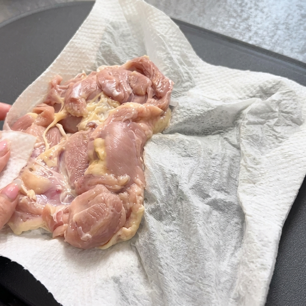 熱したフライパンに鶏肉を入れている様子