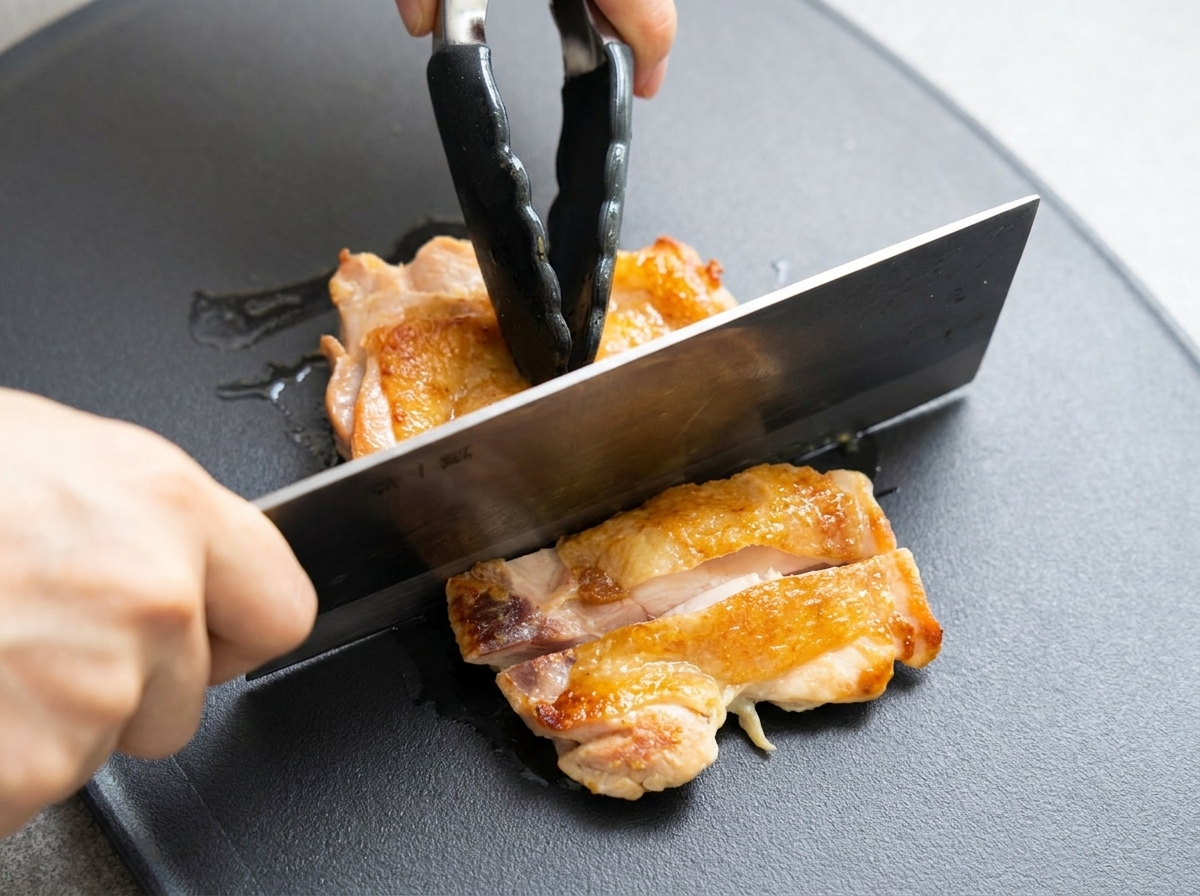 焼けた鶏肉をまな板で食べやすい大きさに切っている様子