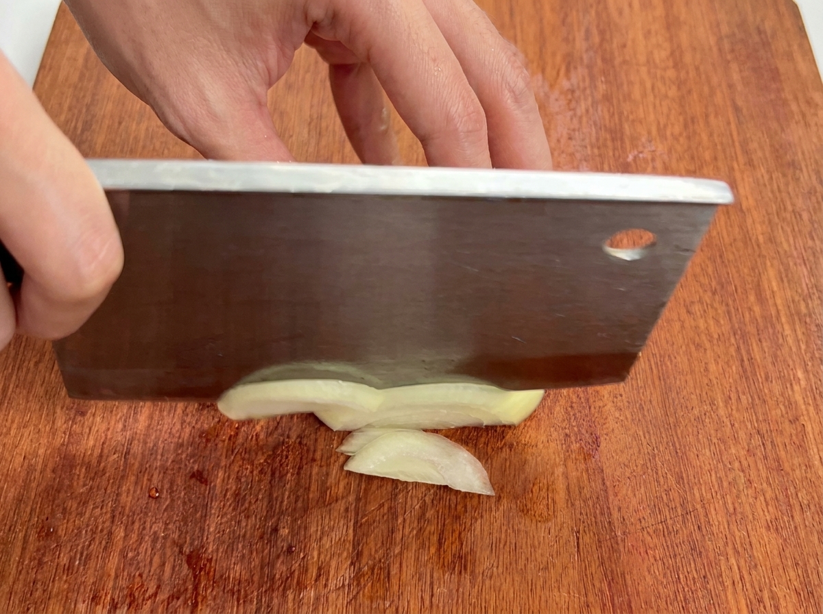 まな板の上で玉ねぎを薄切りにしている様子