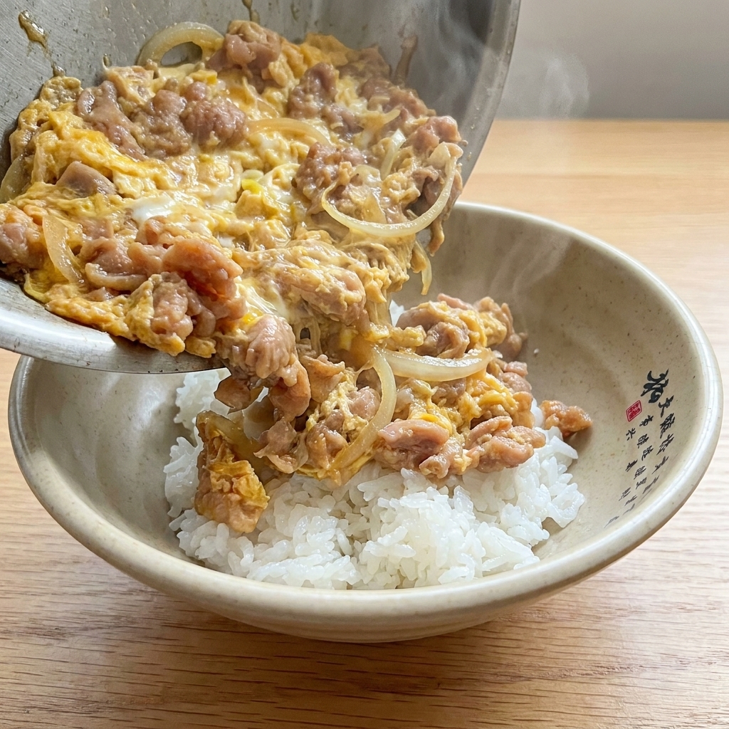 丼のご飯の上に出来上がった他人丼をのせている様子