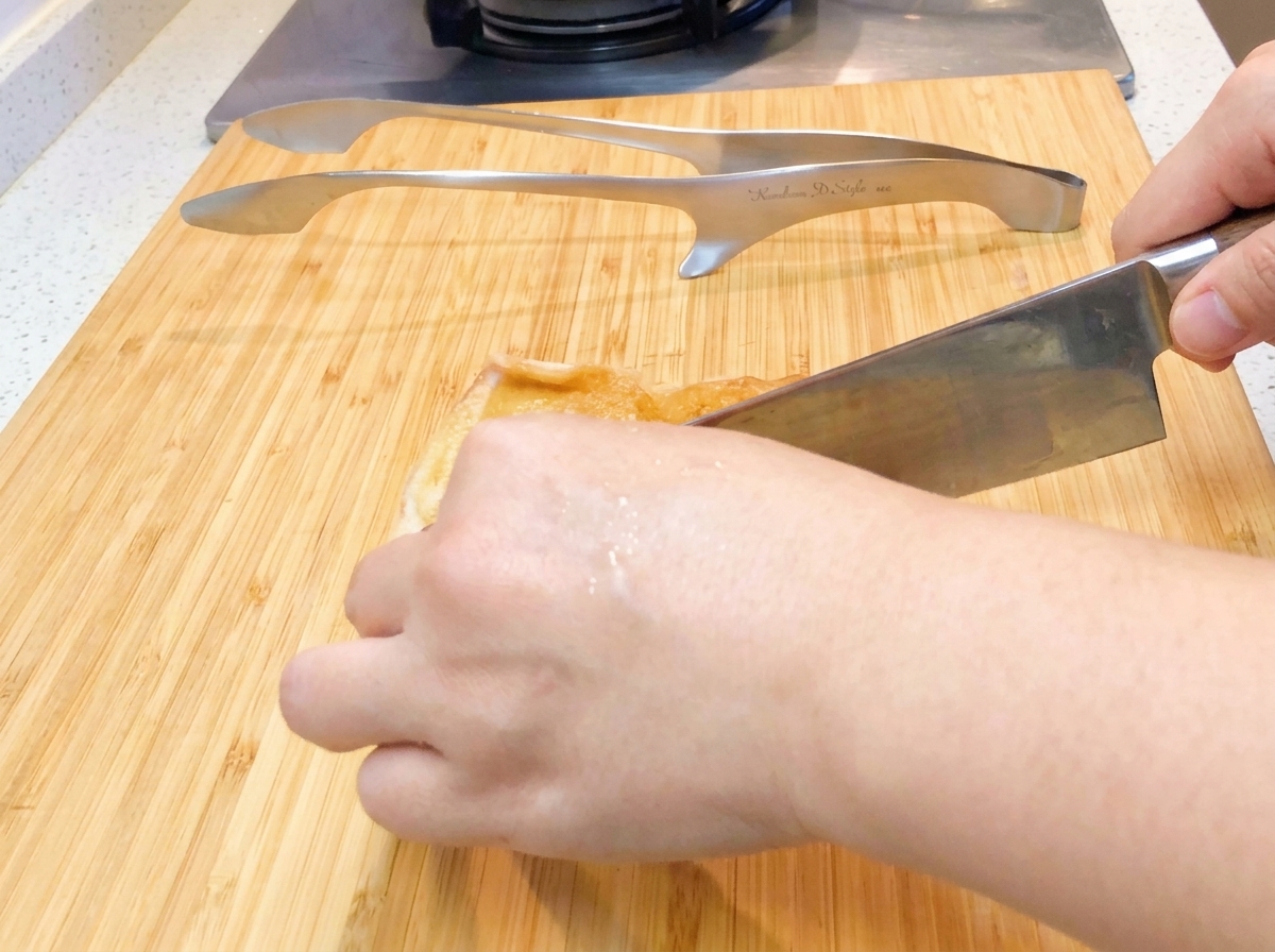 まな板の上で、焼いた鶏肉を一口大に切り分けている様子。
