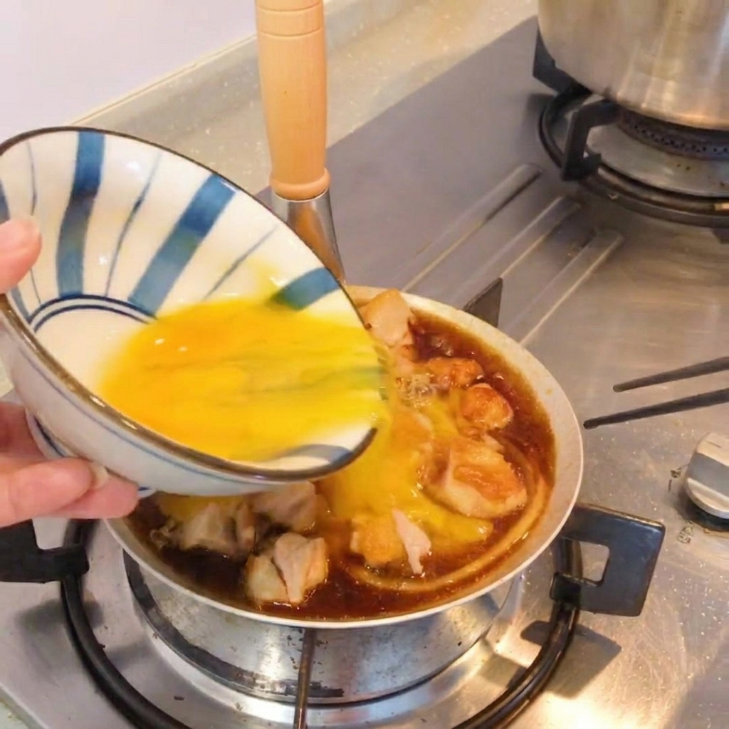 フライパンのまま提供される、新鮮な青ねぎを散らした完成品の親子丼風のおかず。