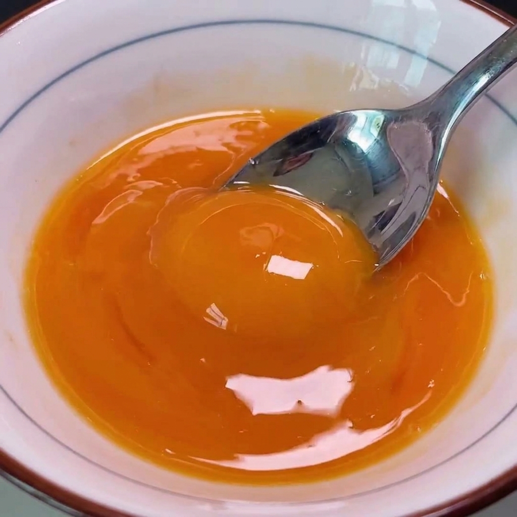 溶いた卵黄を豚カツの上から回し入れている様子。