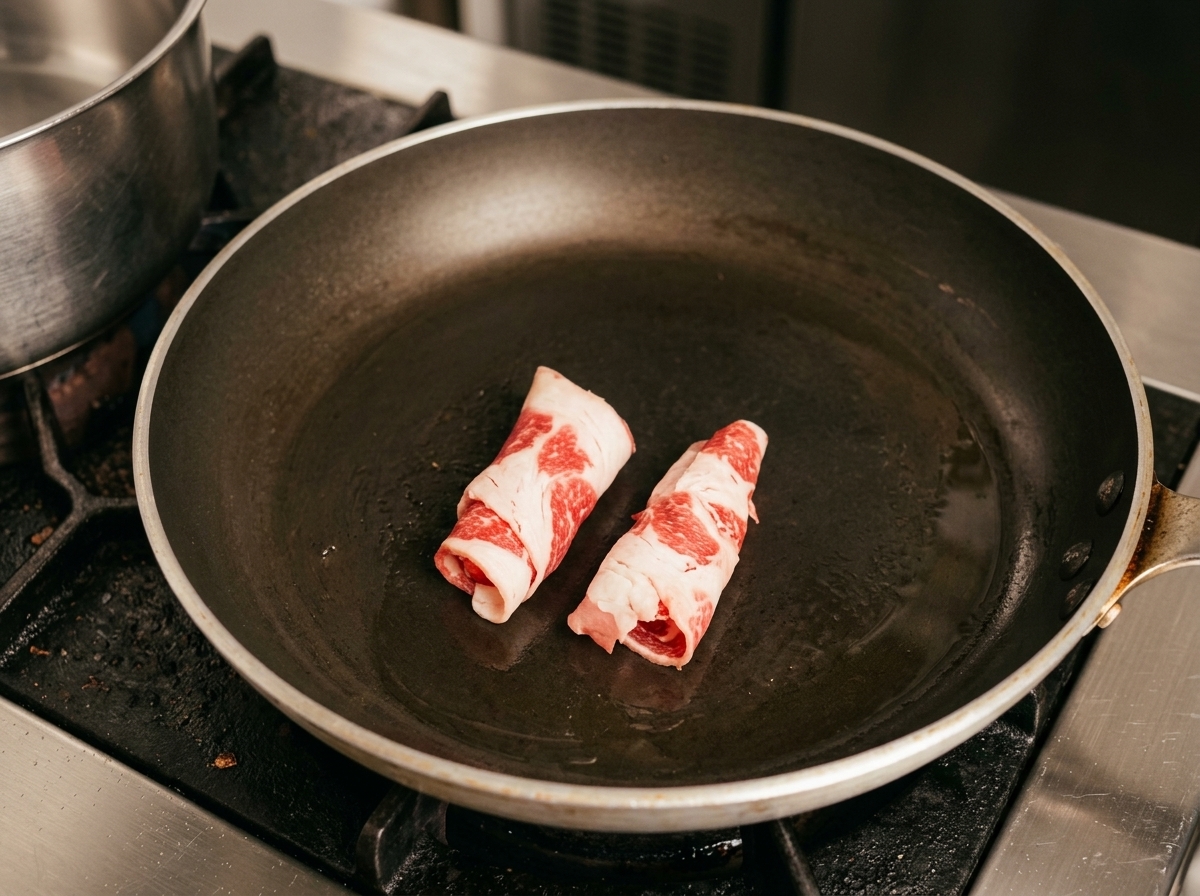 熱したフライパンで牛薄切り肉を焼いている様子。