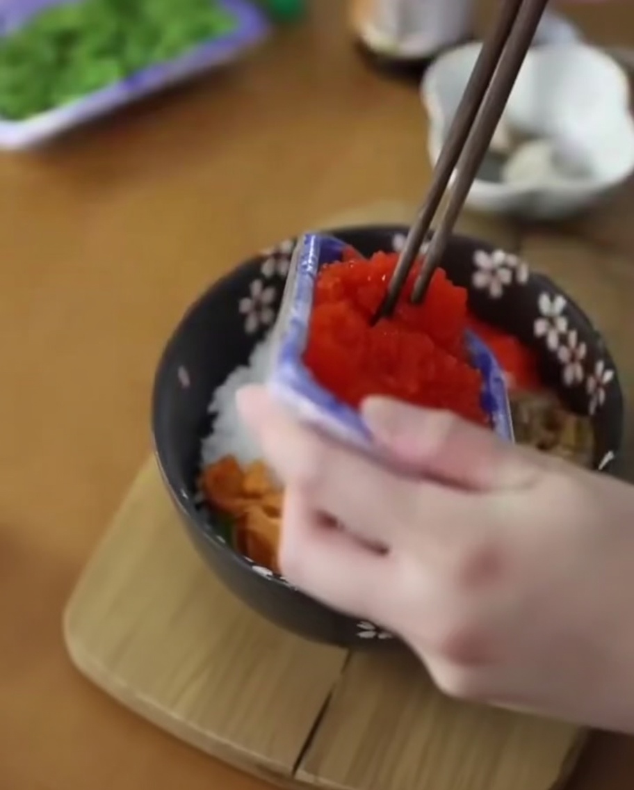 雲丹を載せたご飯の上に、箸でオレンジ色のとびこを添えている。