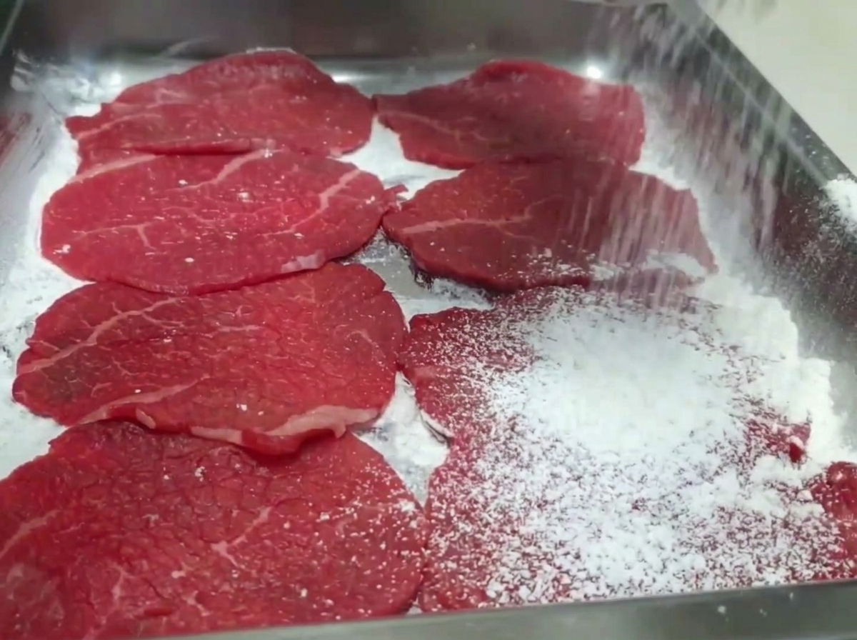 牛肉に薄く小麦粉をまぶしている様子。