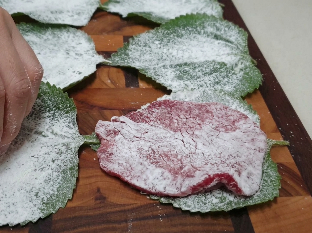粉をまぶしたエゴマの葉の上に、牛肉をのせている様子。
