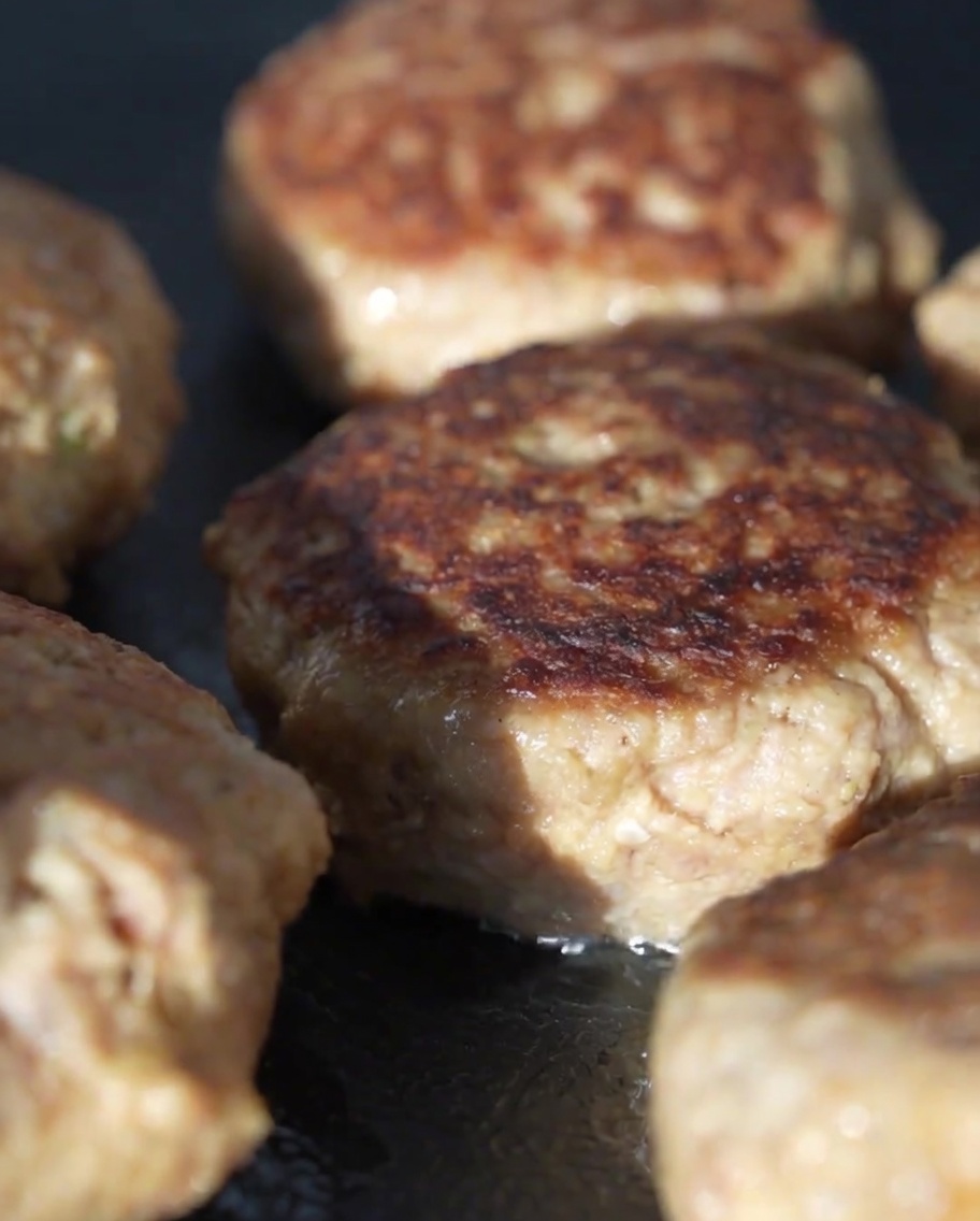 焼いているハンバーグをガラスの蓋で覆って蒸し焼きにしている様子。