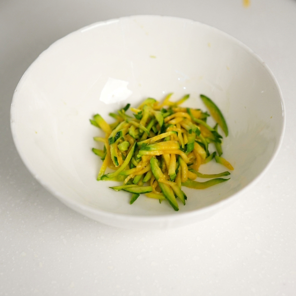 水気を絞ったズッキーニの入ったボウルに、牛ひき肉を加えている様子。