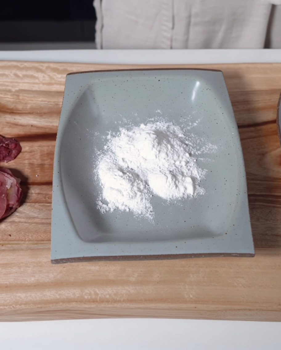 もち粉を入れた浅い角皿と、下味をつけた牛肉。