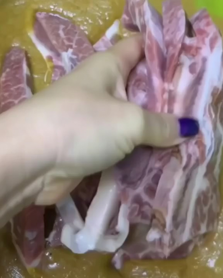 緑色のボウルの中で、肉にタレを絡めている手。