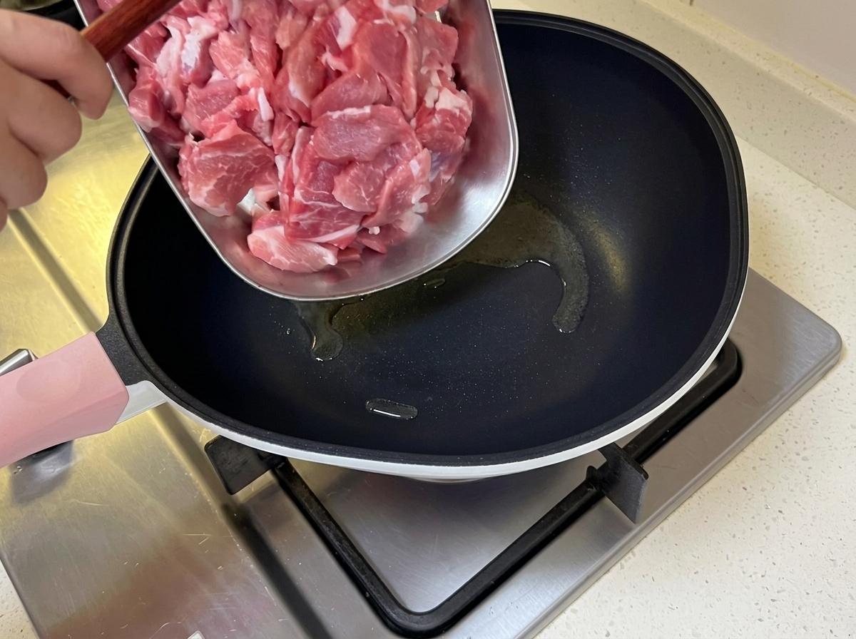 熱したフライパンの油に薄切りの豚肉を加え、炒めている様子。