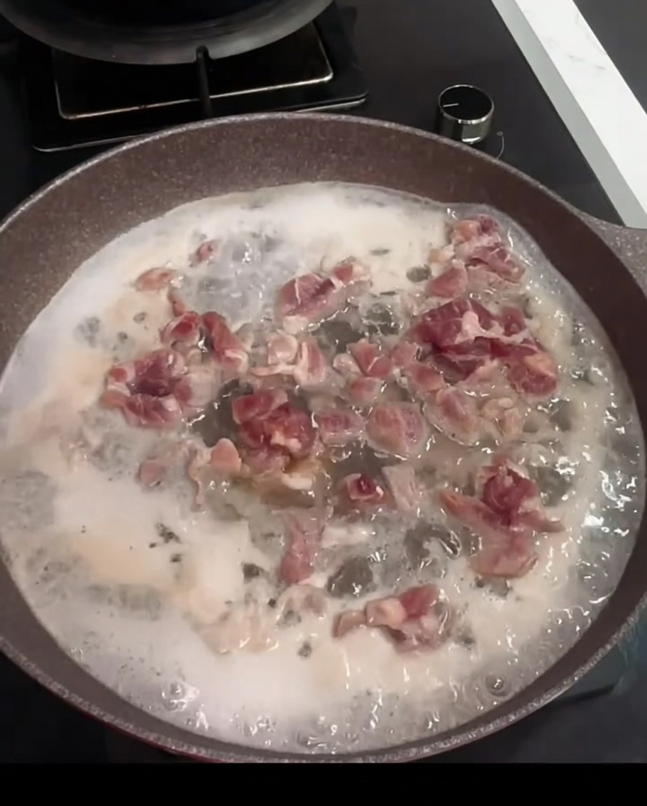 鍋の中で料理酒とローリエとともに茹でられている豚肉。