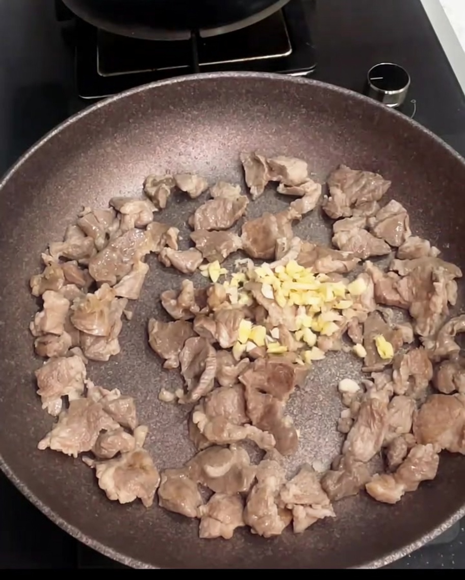 フライパンで豚肉とおろしニンニクが炒められている様子。