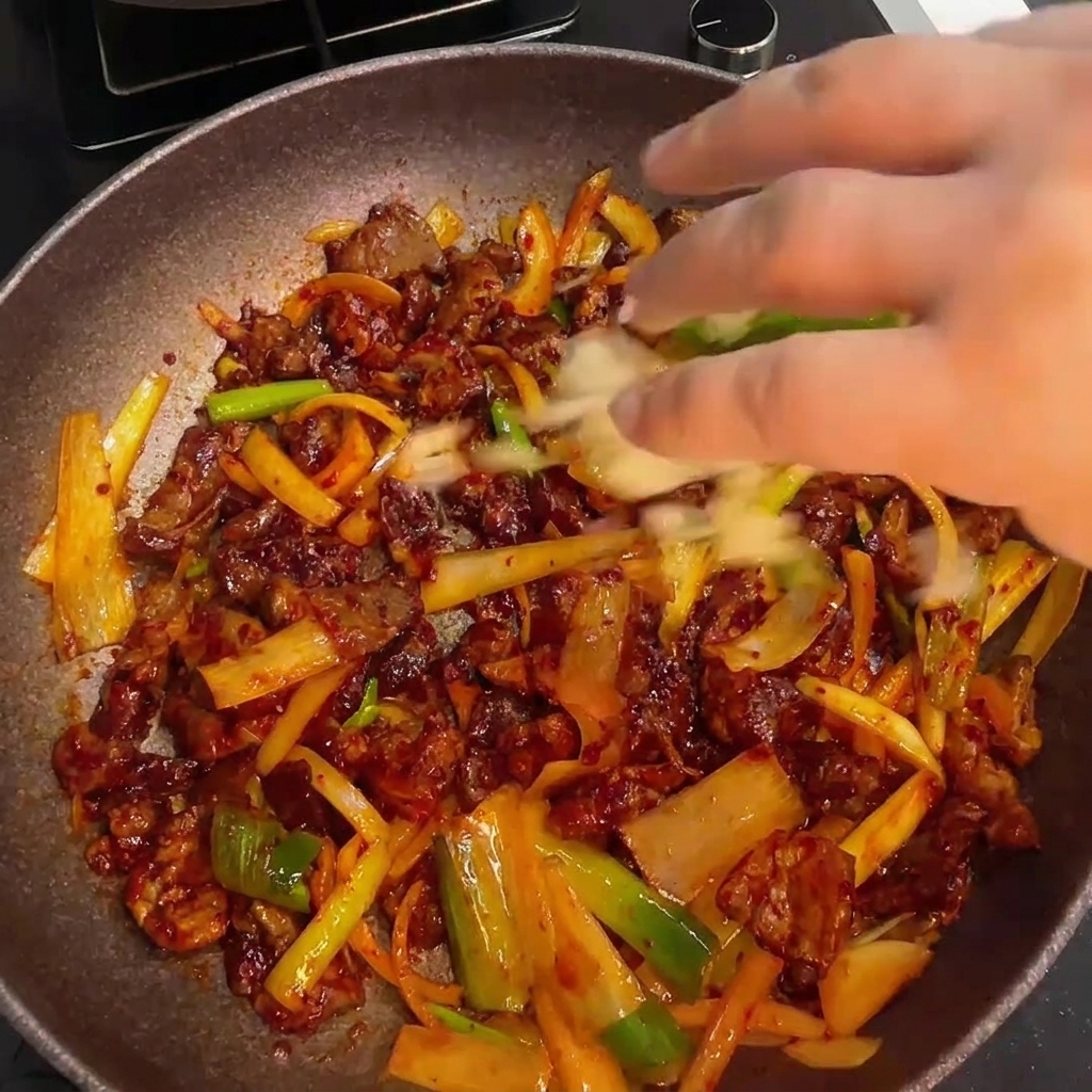 ごま油を回しかけて仕上げている豚肉炒め。