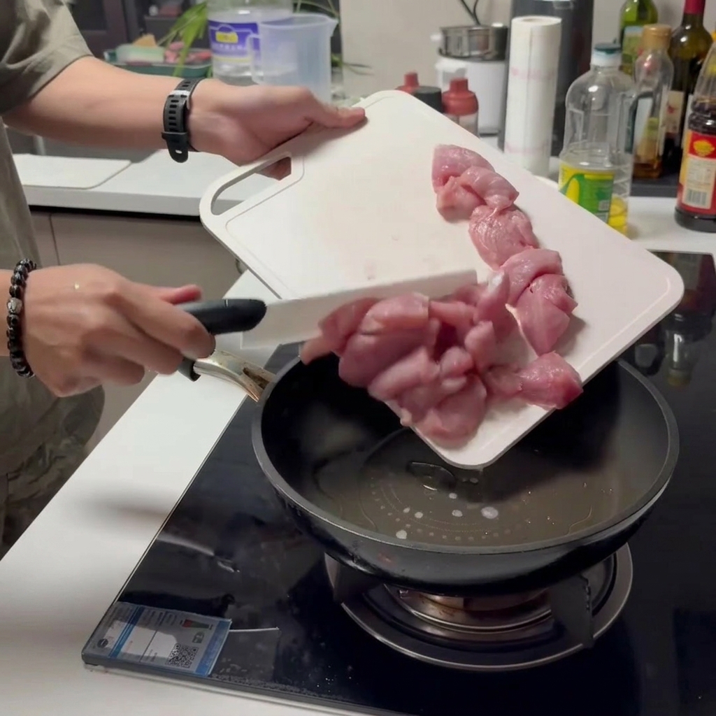 熱したフライパンに切った豚肉を入れている様子。