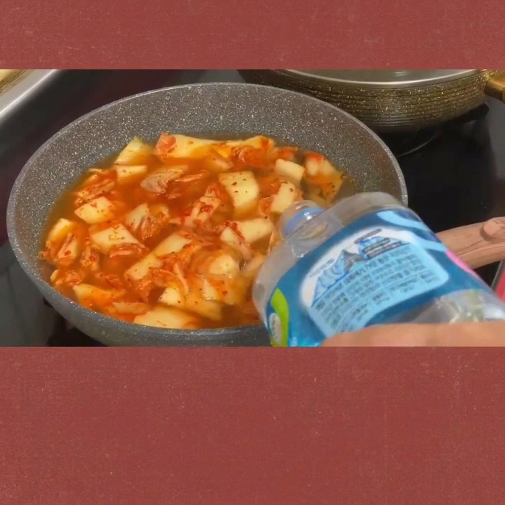 グツグツ煮立つキムチチゲにスライスしたスパムを加えている様子。
