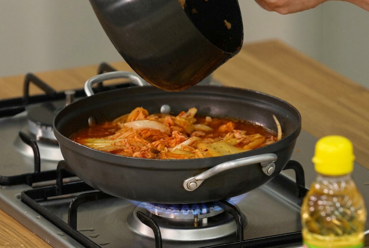 煮立っている鍋に豆腐とネギを乗せている様子。