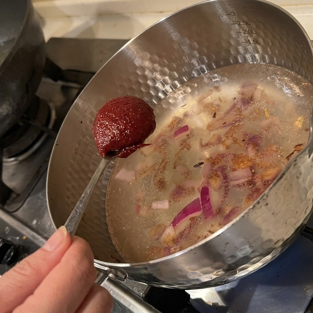 炒めた玉ねぎの入った鍋にコチュジャンを加え、スープのベースを作っている様子。