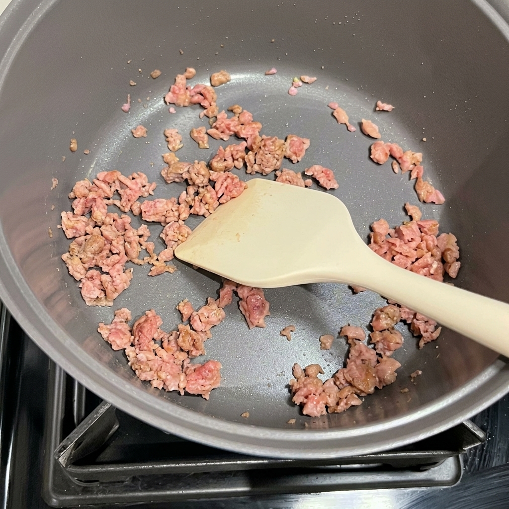 炒めたスパムとキムチを鍋で合わせている様子。