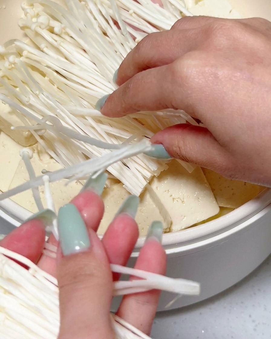 豆腐とスパムの上に、ほぐしたえのき茸と赤唐辛子の輪切りをトッピングしている様子。