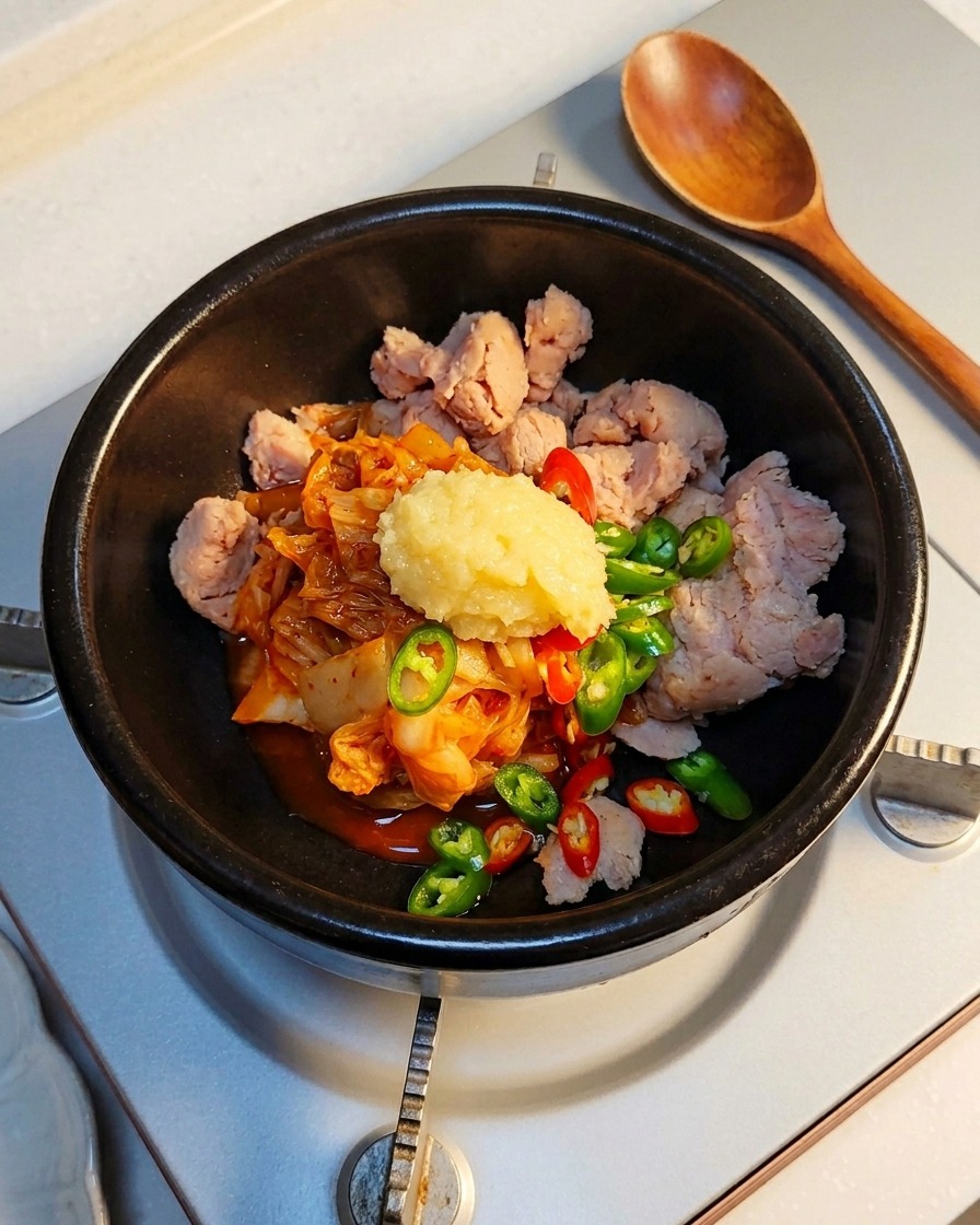 土鍋の具材の上に、おろしにんにくをのせている様子。