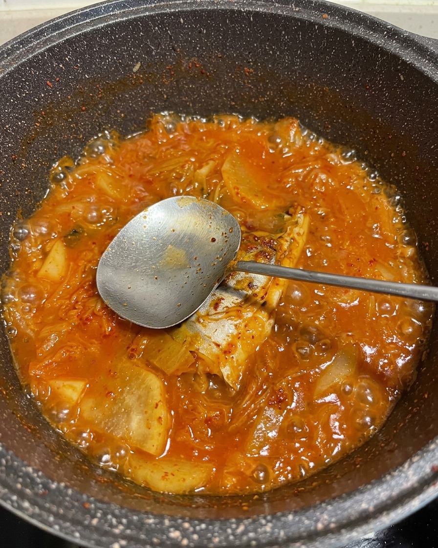 赤い煮汁の中でサバが煮えている様子。