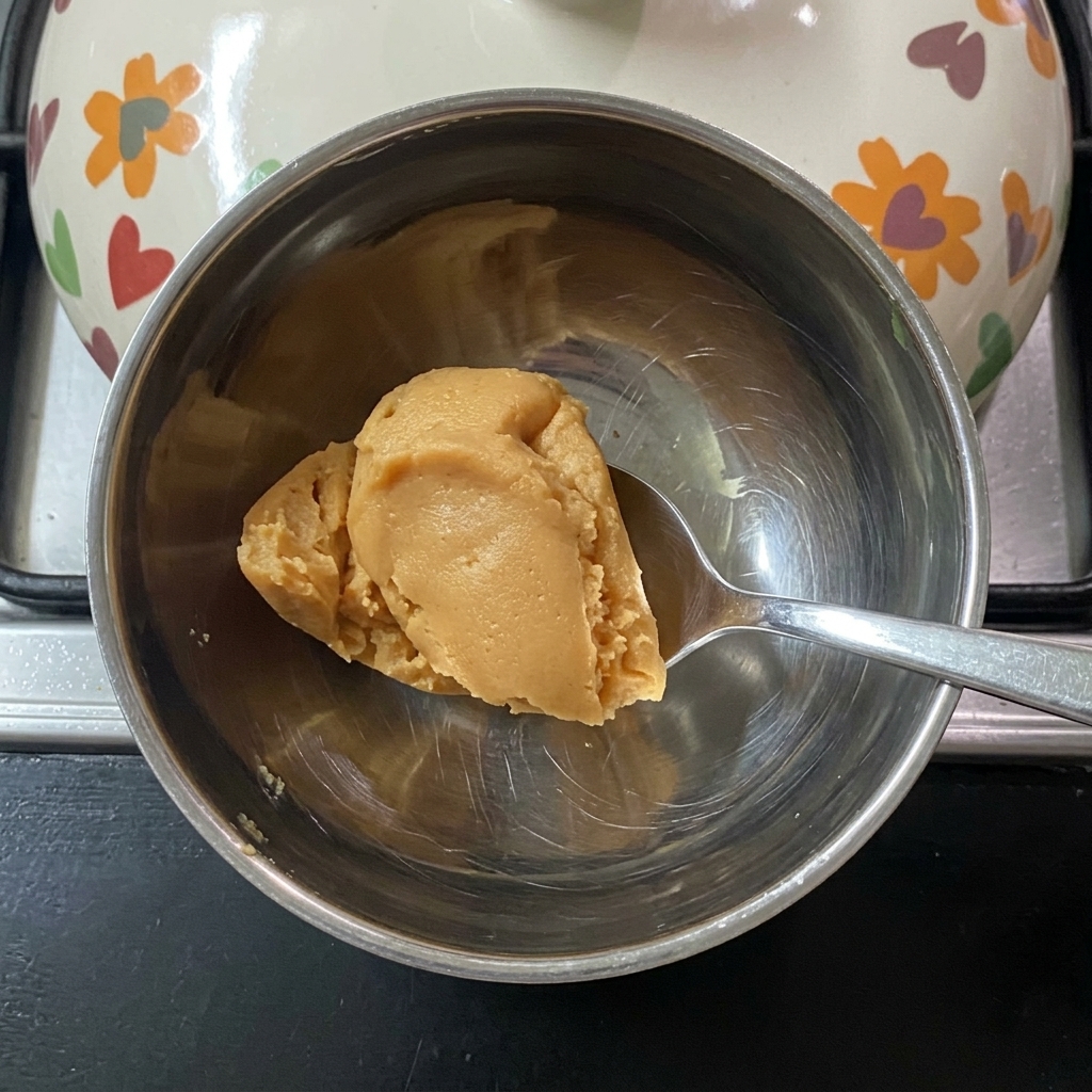 小さな金属製のボウルでお湯を使って味噌を溶かしている様子。