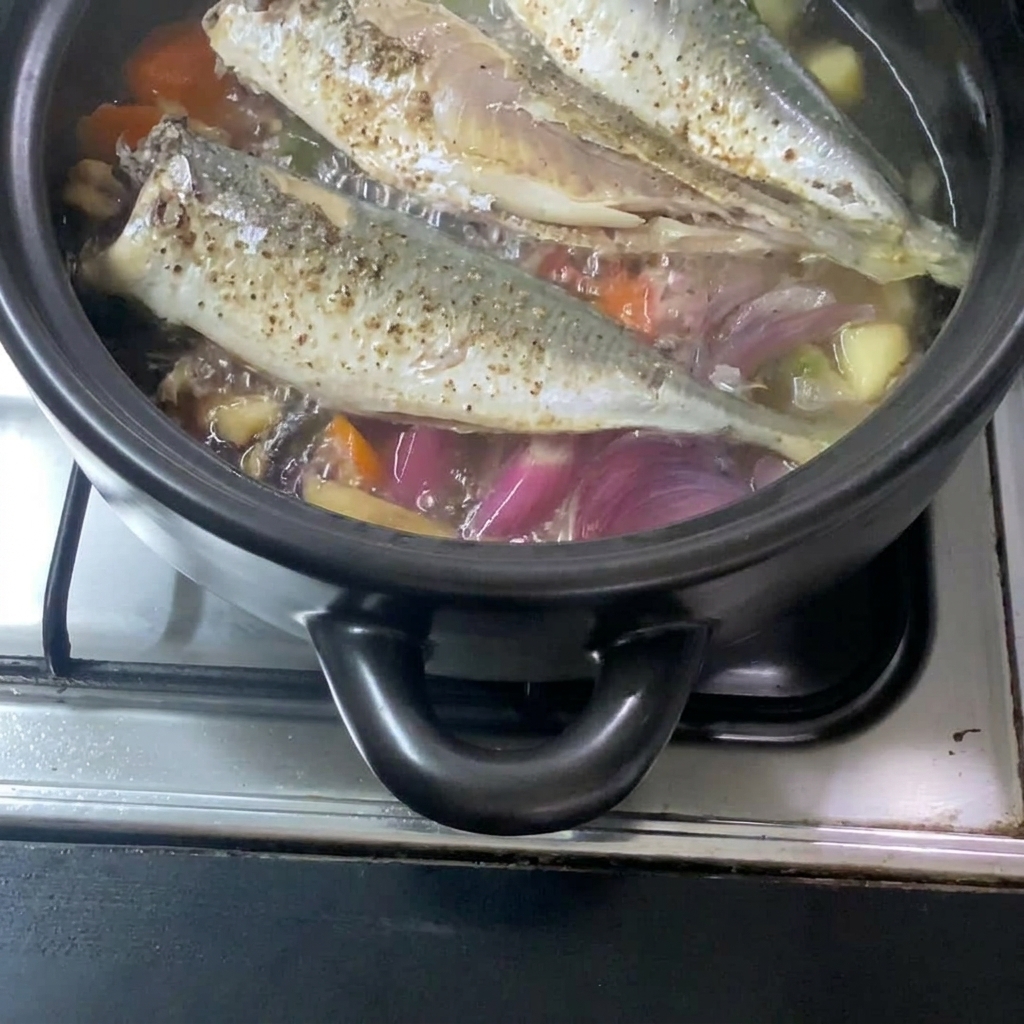 溶いた味噌を土鍋に加え、野菜や鯖と合わせている様子。