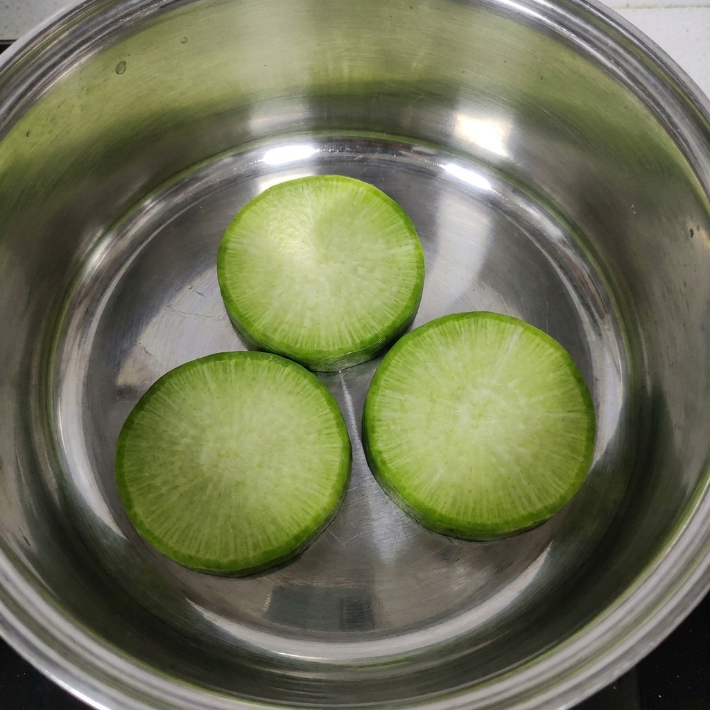 鍋の底に大根の輪切りを重ならないように並べている様子。