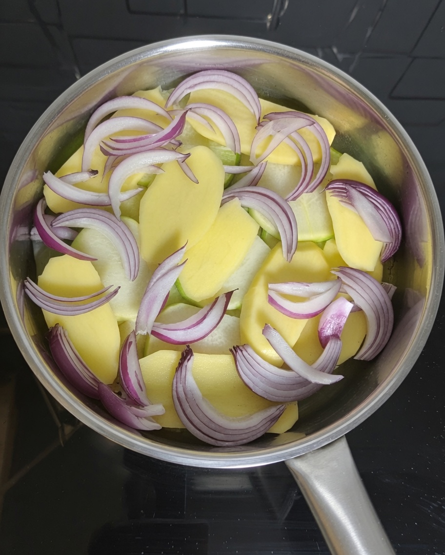 缶から取り出したサバの身を鍋の野菜の上に並べている様子。