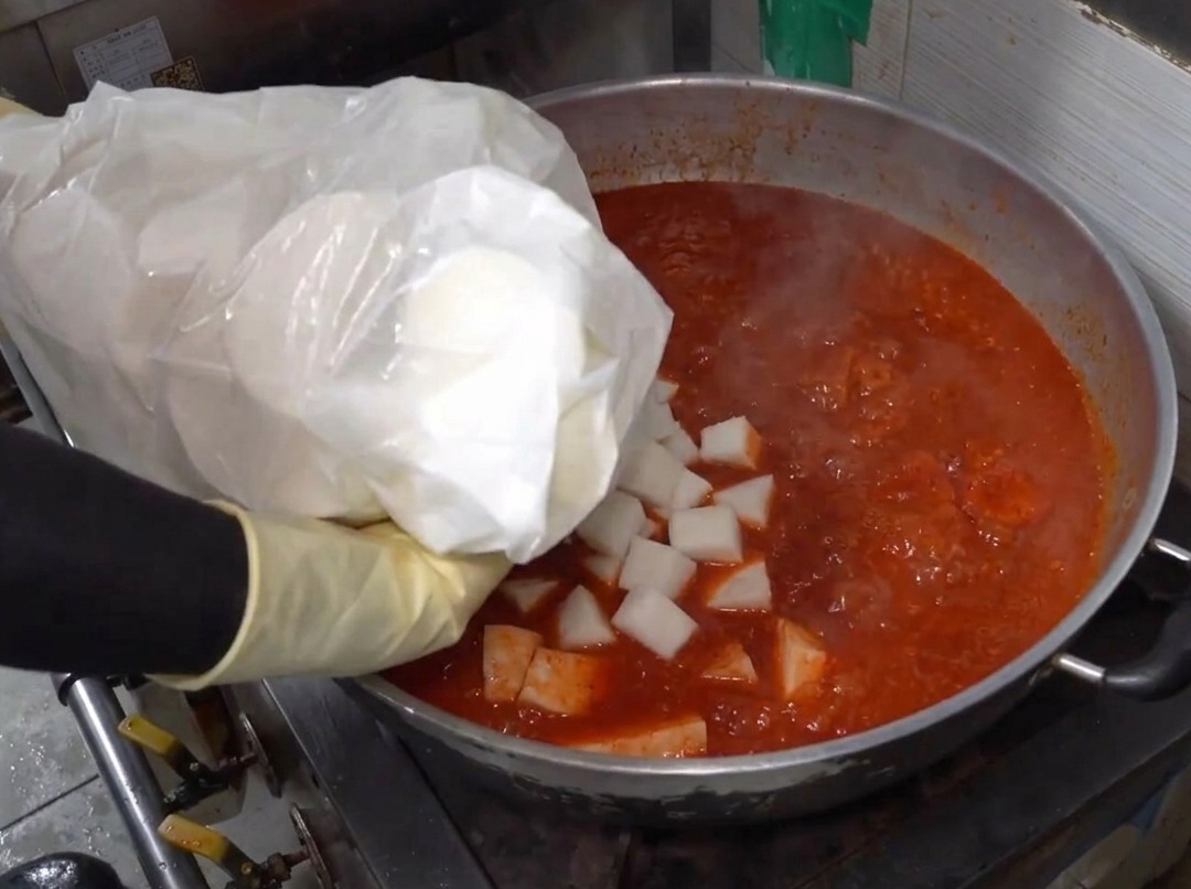 沸騰した旨辛スープの中に大根を入れている様子。