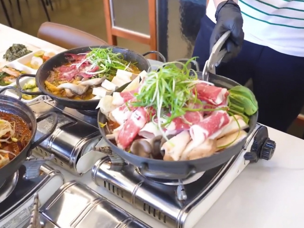 小さめの鉄鍋に、煮込んだ大根とキムチをベースとして敷き詰めている様子。