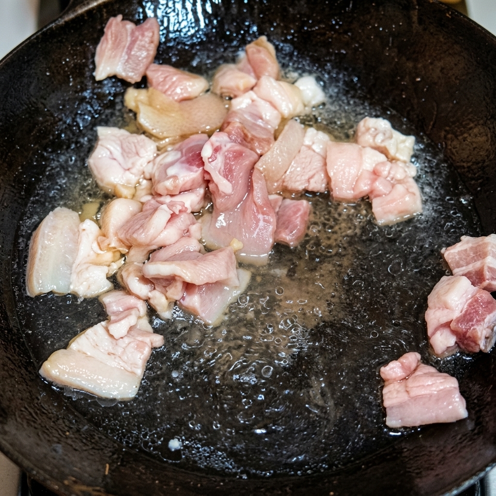 中華鍋でラードを熱し、豚バラ肉をきつね色になるまで炒めている様子。