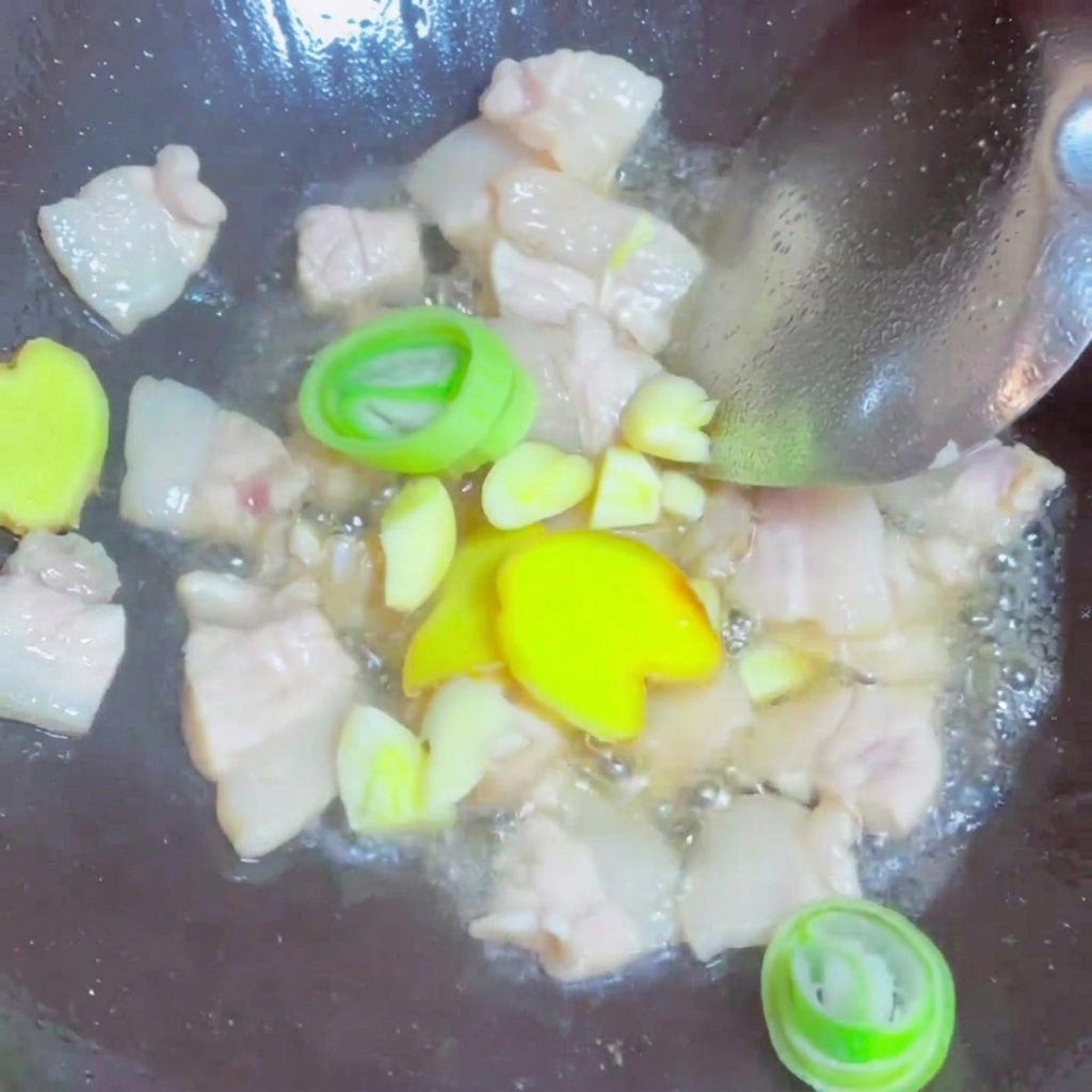 豚肉と一緒に、しょうが、にんにく、長ねぎを炒めている様子。