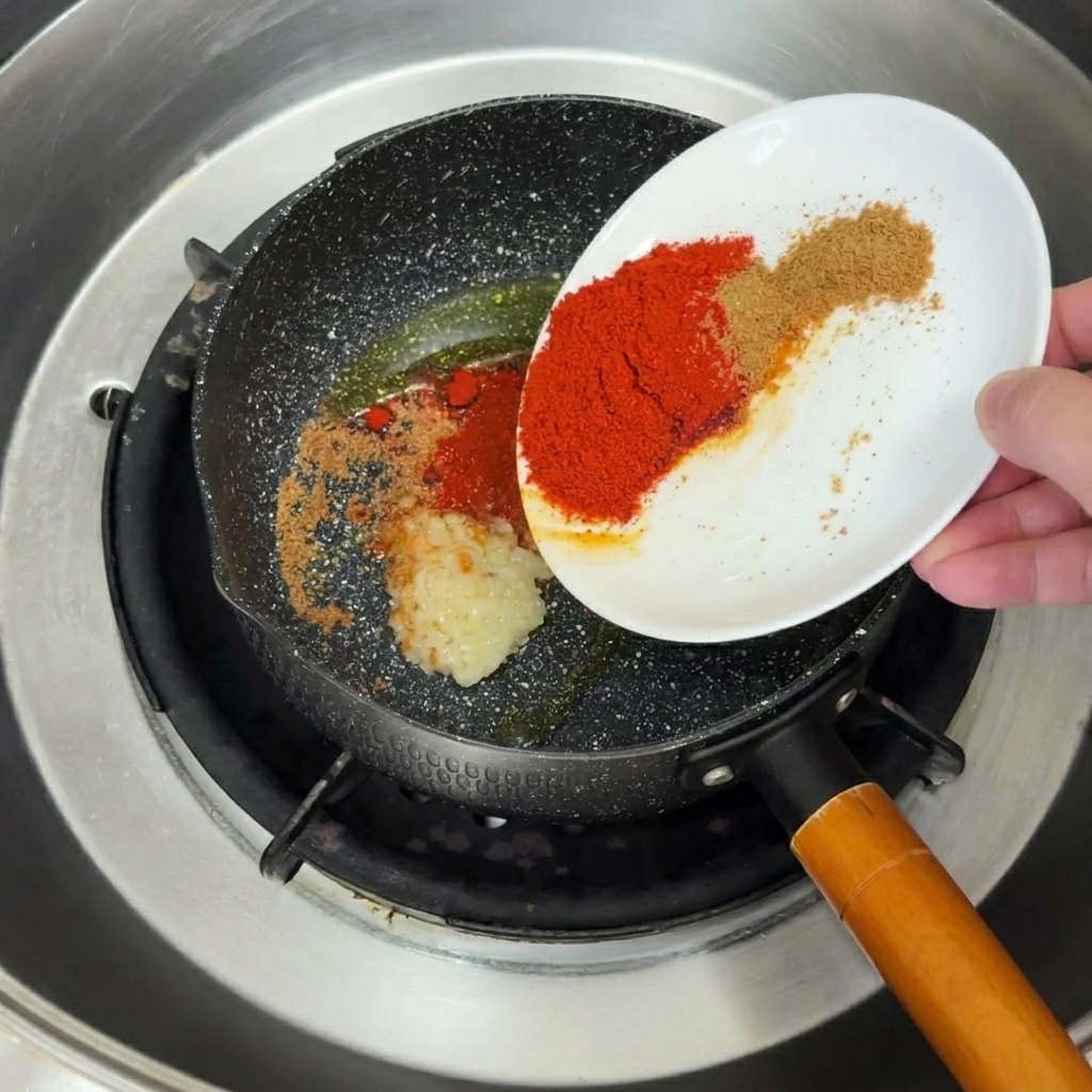 フライパンで熱した油でにんにくとスパイスが炒められている様子。