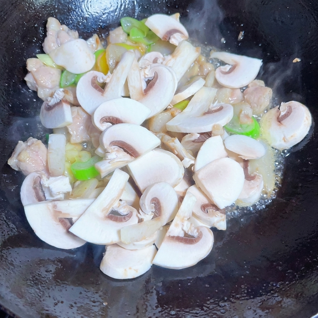 スパイスと一緒に炒められるキノコ、玉ねぎ、もやし。