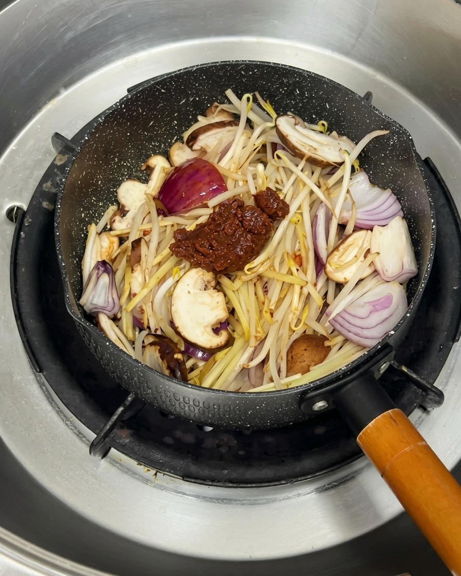 炒めた野菜の中に沸騰したお湯を注いでいる様子。