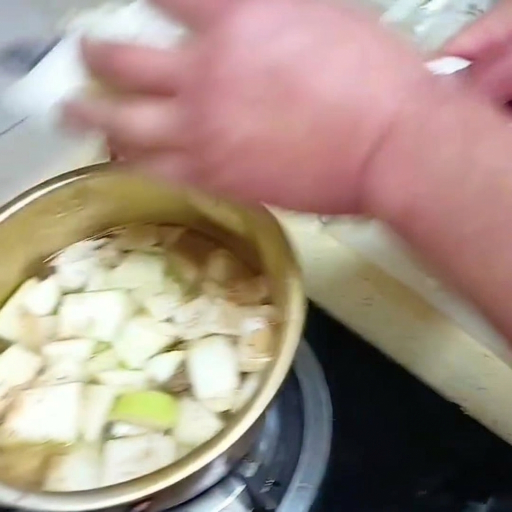 スライスした白菜の葉を、他の野菜と一緒に煮立っているスープの鍋に入れている様子。