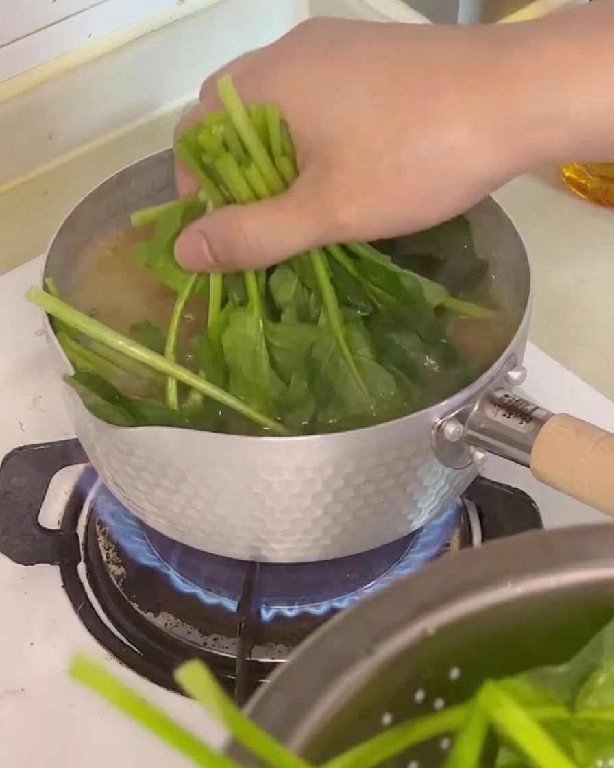 ほうれん草、豆腐、えのき茸を鍋に入れる様子。